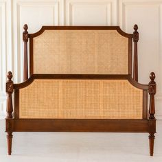 the headboard and foot board of a bed with caned posts, against a white wall