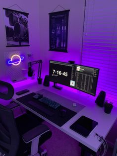 a computer desk with two monitors and a keyboard on it in front of a purple light