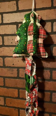 two christmas tree ornaments hanging on a brick wall next to a red and green ribbon