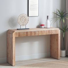 a wooden table with a fan on top of it next to a plant and vase