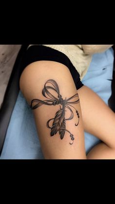 a woman's arm with a tattoo on it that has a bow and feathers