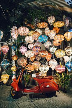 a red scooter parked in front of a building filled with lanterns