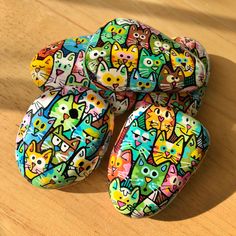 four colorful rocks with cats on them sitting on a wooden table next to each other