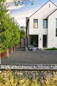 a white house sitting on top of a lush green field next to tall grass and trees