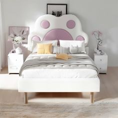 a white bed with pink polka dots on the headboard and foot board in a bedroom