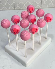 cake pops with pink frosting and sprinkles arranged on a white tray