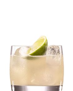 a close up of a drink in a glass with ice and lime on the rim