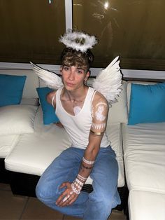 a man sitting on top of a white couch with wings around his neck and arm