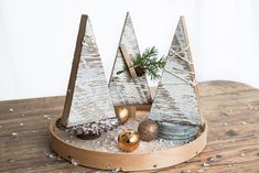 a wooden tray with christmas trees and ornaments on top of it, sitting on a table