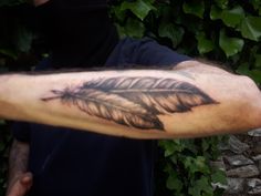 a man with a tattoo on his arm has a feather and is wearing a black mask