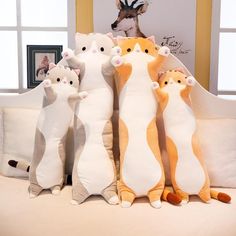 five stuffed cats sitting on top of a bed next to each other in front of a window