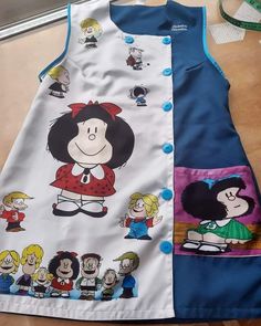 a child's dress with cartoon characters on the front and back, sitting on a table