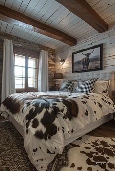 a large bed sitting inside of a bedroom next to a wooden floor covered in cow hide rugs