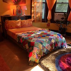 a bed room with a neatly made bed next to two windows and a rug on the floor