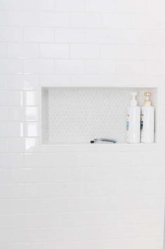 a bathroom with white tiles and a shelf above the toilet