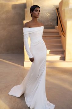 a woman in a white dress posing for the camera with her hands on her hips