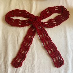 a crocheted red scarf tied on top of a white sheet