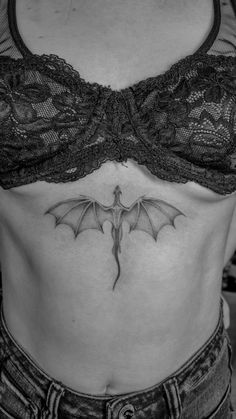 a woman's stomach with a bat tattoo on the side, and an open bra