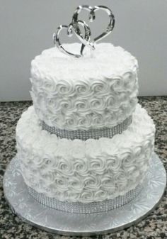 a white wedding cake with two hearts on top