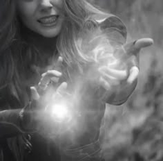 a woman is holding out her hands in front of the camera and light coming from her hand