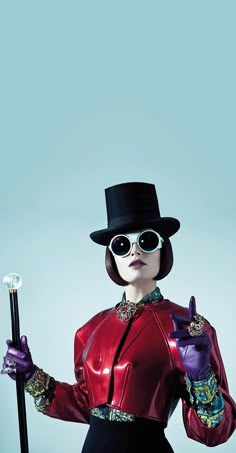 a woman in a top hat and sunglasses holding a cane