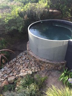 an outdoor hot tub surrounded by rocks and plants