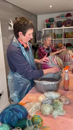 two women are working on yarn in a room with many balls of yarn and crochet hooks