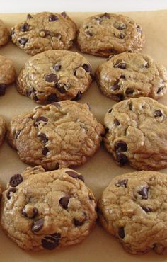 chocolate chip cookies are arranged on a piece of parchment paper