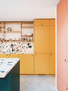 a kitchen with yellow cabinets and marble counter tops