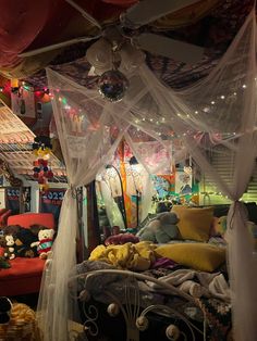 a bed covered in white netting next to a red couch