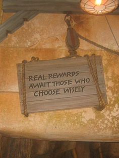 a sign hanging from the side of a building that says, real reward await those who choose wisely