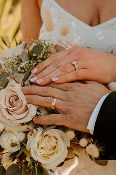 the bride and groom are holding each other's hands with their wedding rings on them