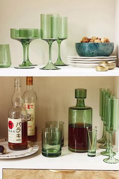 the shelves are filled with different types of glasses and bottles, including one that is green