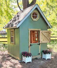 a small green house with two flower pots on the ground