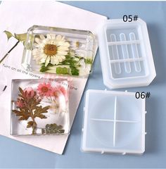 three plastic trays filled with flowers on top of a blue tablecloth next to scissors and paper