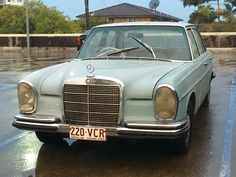 an old mercedes sits parked in the rain