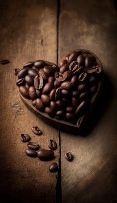 a heart shaped box filled with coffee beans on top of a wooden table next to some seeds