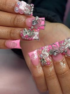 a woman with pink and silver nail polish holding onto her nails, which are decorated with crystal