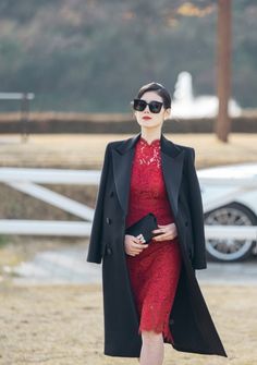 a woman in a red dress and black coat