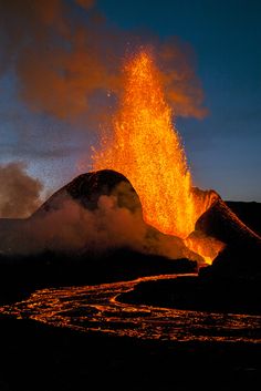 an active volcano spewing lava into the air at night with dark clouds in the background