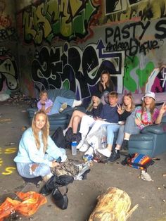 a group of people sitting on couches in front of a wall with graffitti