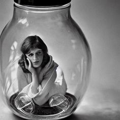 a black and white photo of a woman in a glass jar