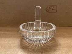 a clear glass bowl with a small toothbrush in the middle on a wooden table