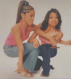 two young women sitting next to each other on the ground with their arms around one another