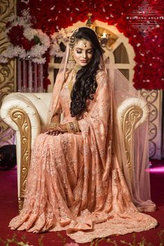 a woman sitting on top of a white couch wearing a pink dress and headpiece