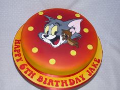 a red and yellow birthday cake with an image of tomy and jerry on it