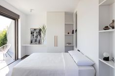 a white bed sitting in a bedroom next to a sliding glass door