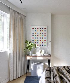 a bed room with a neatly made bed next to a window and a painting on the wall