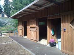 the outside of a horse barn with several stalls