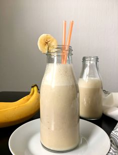 a banana sitting on top of a white plate next to a glass filled with milk